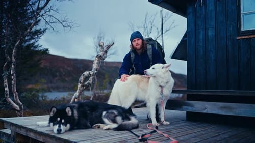 Man With His Pet Dogs Resting Outside A Cabin In Åfjord, Norway - Static Shot