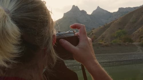 Portrait of woman photographer taking pictures on vintage camera beautiful mountain landscapes