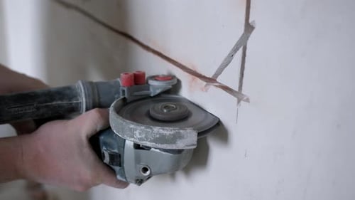 Electrician Using Angle Grinder to Create Cable Channels in Wall for Wiring Installation