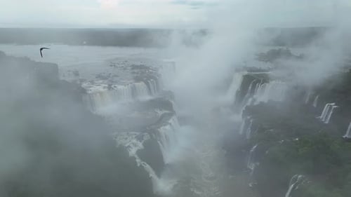 Aerial View of Iguazu Falls Stretching Along Border with Mist and Rainforest