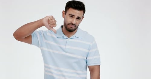 Thumbs down, face and hands of man in studio for rejection of bad news, emoji sign
