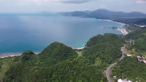 Aerial view of tropical beach and turquoise sea water with small waves close to green mountains.