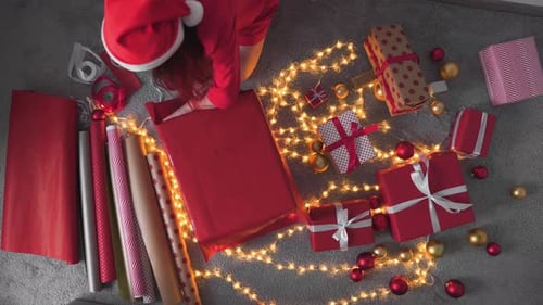 Woman Wrapping Christmas Gifts on Floor at Home