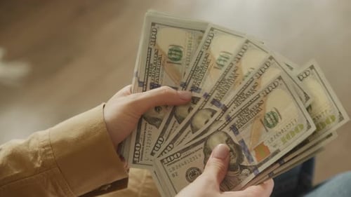 Woman counting United States hundred dollar bills