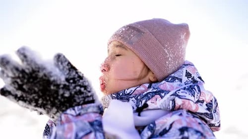 Girl Blowing Snowflakes in Winter Sunlight