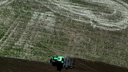 Aerial top view of a tractor sowing in the fields, agro working in the field.