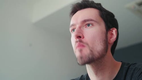 Young caucasian man bites into burger at home, cheeseburger eating enjoyment, close up portrait fast