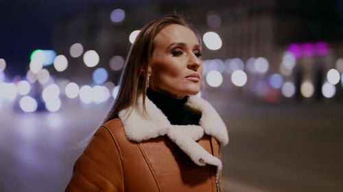 Belo rosto esbelto de uma mulher na paisagem noturna das ruas da cidade