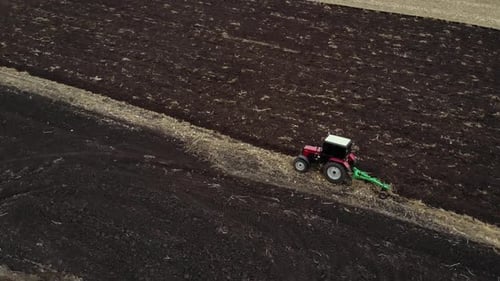 Red tractor plowing the field in Ukraine