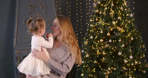Young Woman Holding Little Daughter Near Christmas Tree