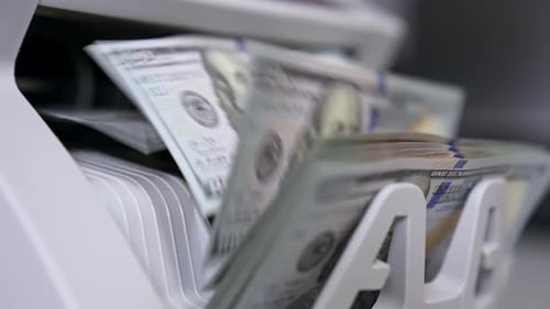 Máquina contadora de dinero. El mostrador de billetes cuenta billetes de cien dólares. Primer plano