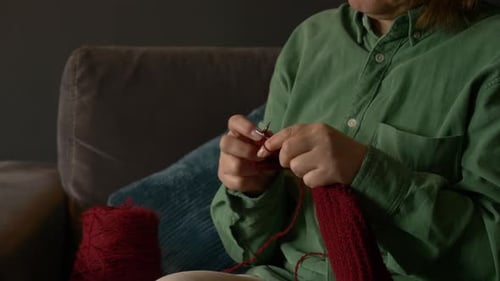 Alte Großmutter strickt zu Hause auf der Couch einen Pullover