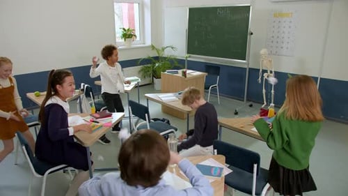 Elementary School Class Children Communicate with the Teacher Answering Question