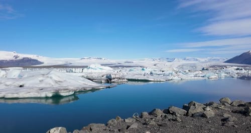 Witness the tranquil beauty of Iceland's winter wonderland, where two ducks glide effortlessly on a