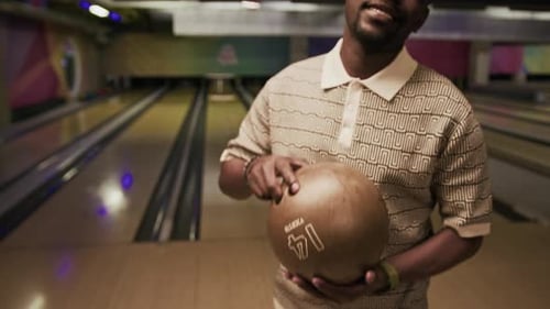 Portrait of African American Guy with Bowling Ball on Alley
