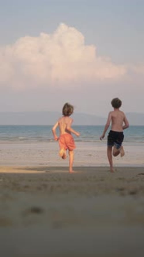 Boys Run Joyfully Toward The Sea Under A Clear Sky