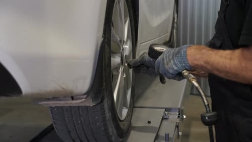 Un mécanicien vérifie la pression dans les roues d'une voiture dans une station-service