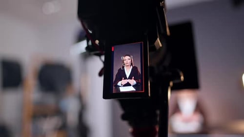 Caucasian brunette talking and gesturing on the display of the professional camera. Close up.
