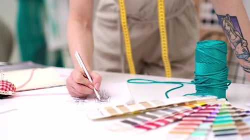 Woman Tailor Draws Glamorous Dress Sketch with Pencil at Desk Working in Fashion Atelier