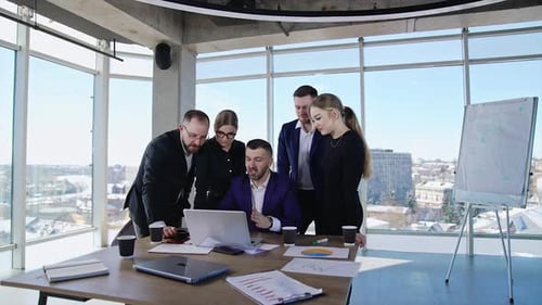 Team Discussing Data at Table in Bright Office
