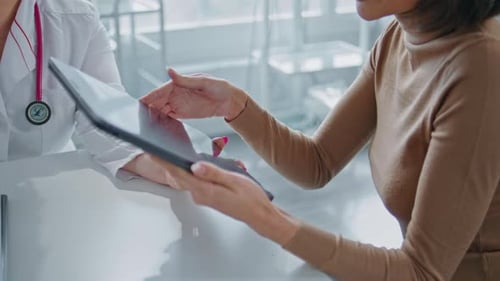 Doctor Consults with Patient on Tablet in Office
