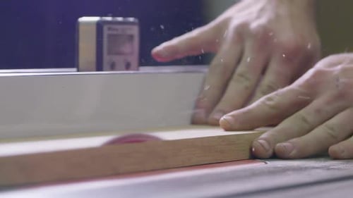 Man cuts wood on a table saw in his shop