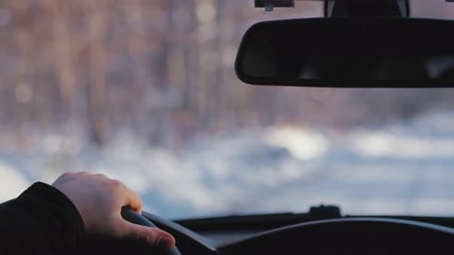 Inside view of unrecognizable man driving car during the winter. Shot with RED helium camera in 8K.