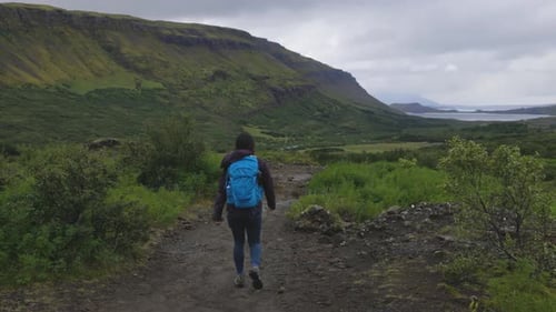 Gorgeous wide shot of a young woman hiking through the mountain paths in Iceland