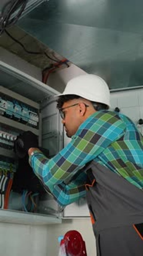 Electrician Working on Electrical Panel Installing Cables and Breakers