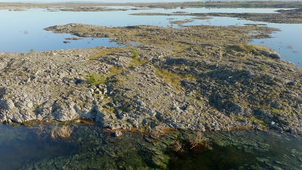 Sharp jagged limestone rocks protrude from flooded mossy waters in the ...
