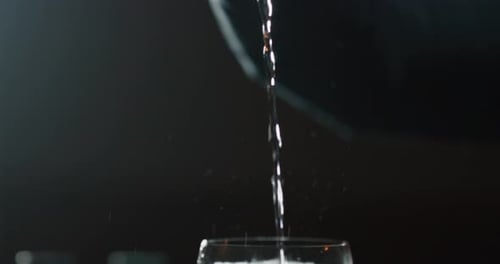 Close up of a professional bartender is preparing an alcoholic cocktail with ice cubes to customer