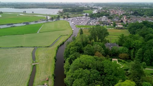 A narrow water channel winds through a green forest, reflecting the surrounding trees.