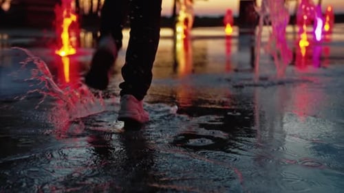 Fun of Happy Person Running on Water Fountain Outdoors at Summer Night in Park