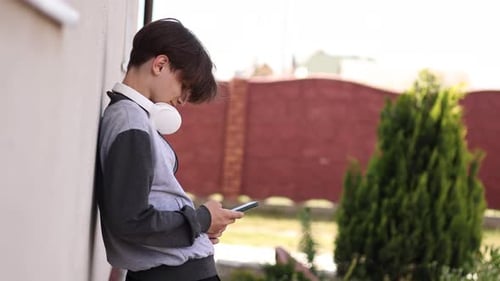 Teen Leaning Against Wall Using Mobile Phone