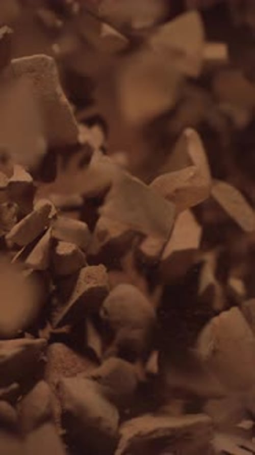 Top View of Raw Chocolate Chunks with Powdered Chocolate Flying in Super Slow Motion Pieces of