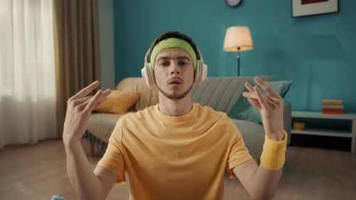 A Man in Headphones Listens to Music From a Smartphone Sits in a Lotus Position Meditates Does Yoga