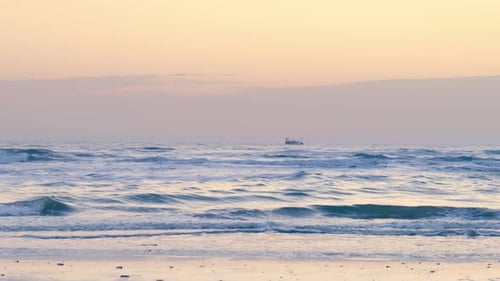 A fishing boat in the distance on a calm ocean during a pastel-colored sunset