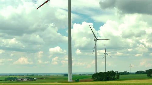 Luftaufnahmen, die eine Reihe von Windturbinen zeigen, die hoch über grünen landwirtschaftlichen Feldern stehen