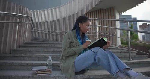 Young Adult Studying Outside With Coffee and Notebook