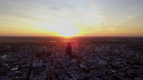aerial shot of sunrise in a city, while the sun rises from behind a building in a sky full of colors