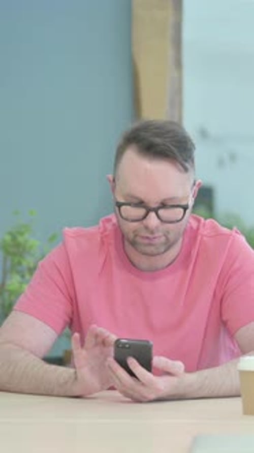 Man Typing on Phone Indoors at Office Desk