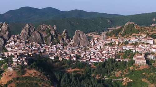Aerial drone of Pietrapertosa, Italy—mountain village built into rocky peaks, terracotta roofs,