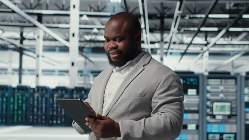 Engineer Working in Server Farm Using Tablet to Analyze Data