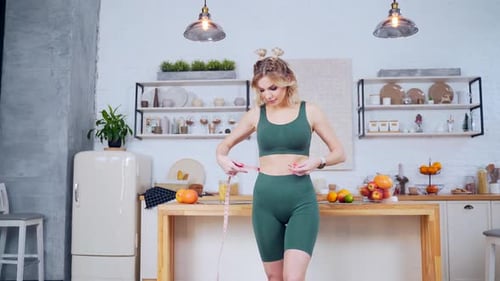 portrait d'une jeune femme en forme avec une silhouette élancée et une taille fine en vêtements de sport, mesure la taille