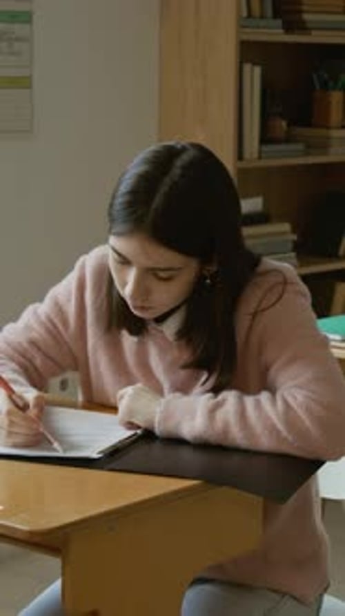 Vertical of Focused Caucasian Female Student Writing Test at Lesson