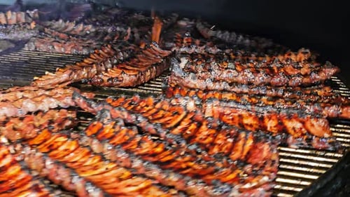 Grilled Ribs Cooking on a Barbecue Smoker Rows of Succulent Charred Ribs Cooking on a Barbecue