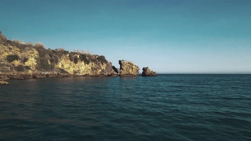 Drone flying forward at a rocky coastline