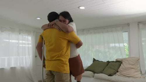 Woman Embracing a Man on Crutches Indoors