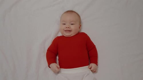 Smiling Infant Lying on White Blanket