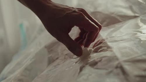 Hombre que usa una aspiradora para eliminar el aire de una bolsa de plástico llena de una acogedora manta